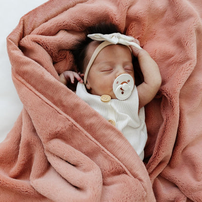 Baby sleeping wrapped in Saranoni Receiving Lush Blanket - Clay