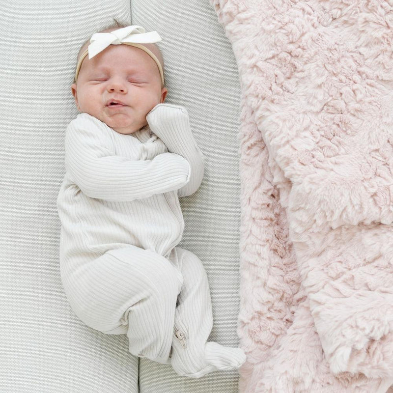 Sleeping baby next to Saranoni Receiving Dream Blanket - Blush