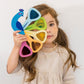 Little girl looks through Tender Leaf Toys Peacock Colors Toy