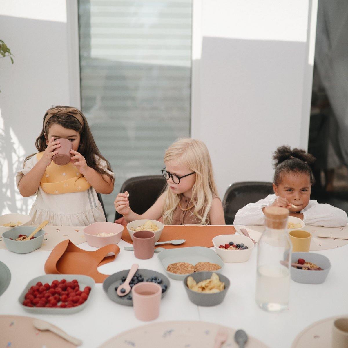 Girls eating breakfast on Mushie Silicone Place Mat