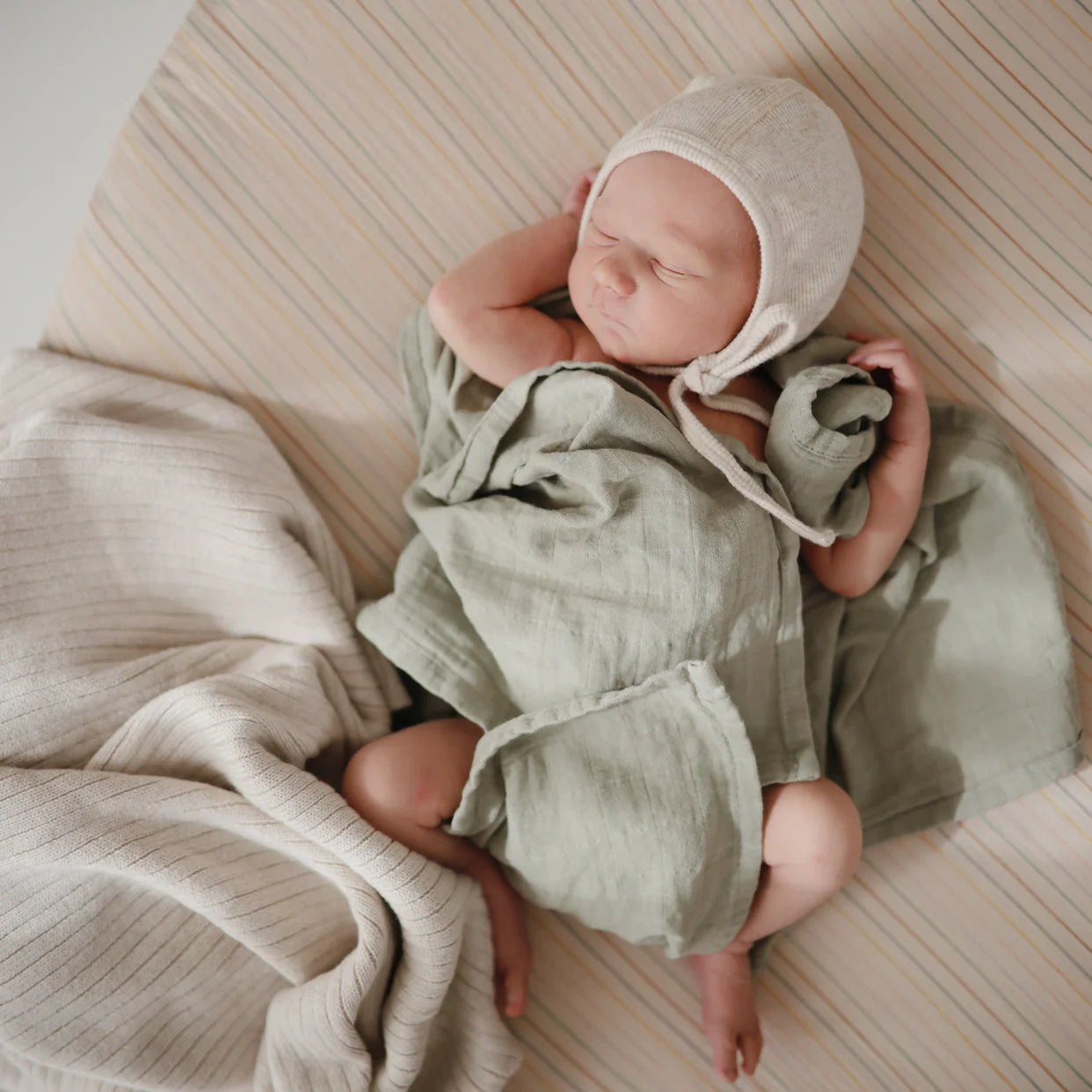 Newborn baby sleeping next to Mushie Knitted Ribbed Baby Blanket - Beige Melange