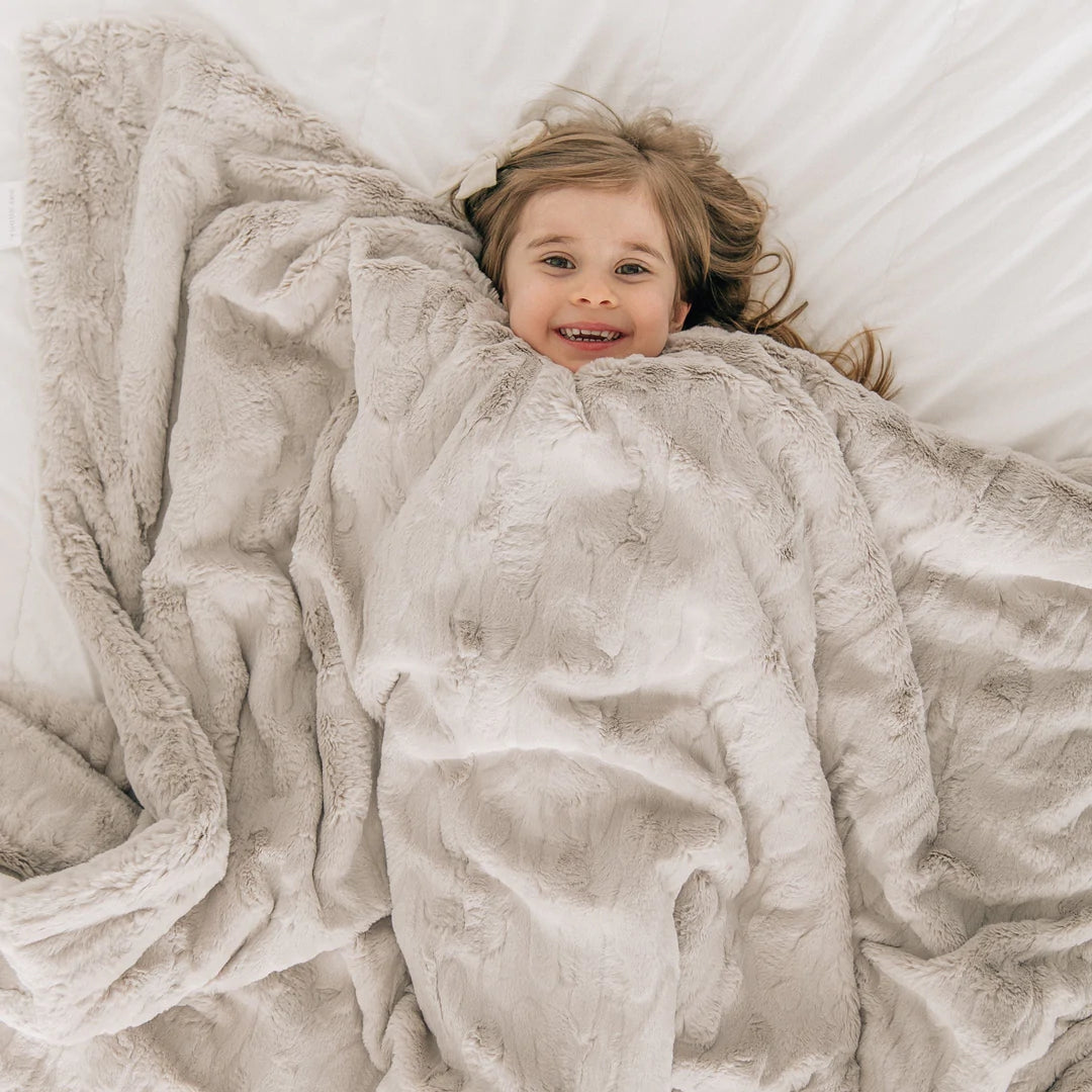 Little Girl laying in Saranoni Patterned Faux Fur Throw Blanket - Feather