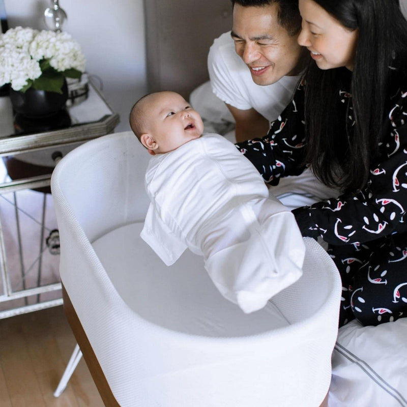 Parent places baby in Happiest Baby SNOO Smart Sleeper - White