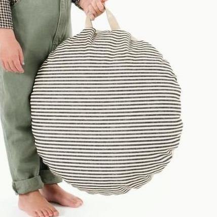 Child holds Gathre Mini Circle Floor Cushion - Stone Stripe